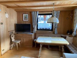 een woonkamer met een tafel en een tv bij Appartamenti Hacoli in Selva di Val Gardena