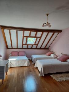 two beds in a room with wooden ceilings at La Grange de Lily in Vic-sur-Cère