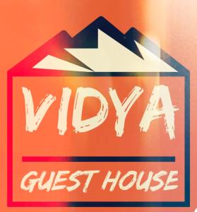 a sign for a guest house with an arrow at Vidya Guest House in Katra