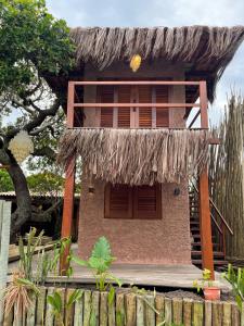 a house with a straw roof and a wooden fence at Vulva Caraíva Hostel e Pousada para Mulheres in Caraíva