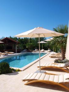 basen z leżakami i parasolem w obiekcie Apartments Villa Učka w mieście Opatija