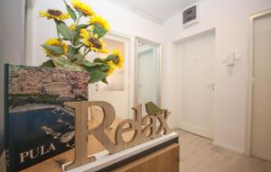 Znak na korytarzu z wazonem słoneczników w obiekcie Apartman Nonno w Puli
