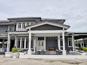 ein Haus mit einer Veranda mit Tischen und Stühlen in der Unterkunft Cottage Garden in Penampang