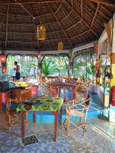 a restaurant with tables and chairs and people in the background at Fontaine Garden Village in Bwejuu