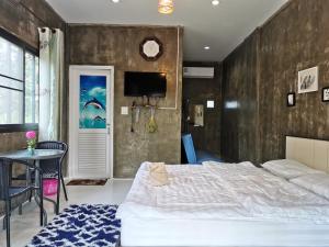 Schlafzimmer mit einem Bett, einem Tisch und einem TV in der Unterkunft Home Garden Chaeson บ้านสวน ชวนฝัน in Lampang