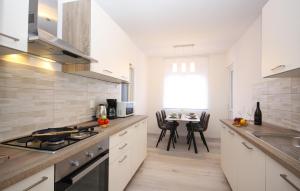 a kitchen with white cabinets and a table with chairs at Apartman Nonno in Pula