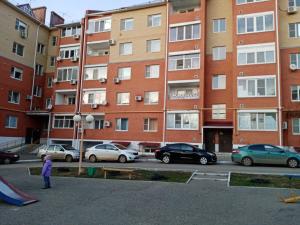 a child standing in a parking lot in front of a building at Уютная двушка in Elista