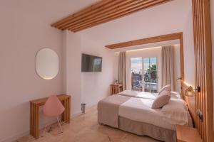 a bedroom with a bed and a desk and a window at Hotel Boutique Sibarys - Adults Recommended in Nerja