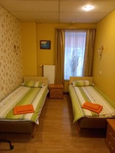 dwa łóżka w pokoju z oknem w obiekcie Apartment Hotel Rubini w mieście Windawa