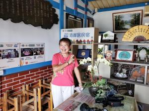 Una donna in piedi davanti a un tavolo in un negozio di 嘉義泊岸居民宿 a Lucao