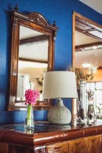 a lamp on a table with a mirror and a vase of flowers at Hotel Vineyard Inn - Szőlőskert in Nagykanizsa