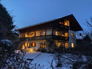 una casa grande en la nieve por la noche en Charmantes Garten-Apartment: Erholung im Chiemgau, en Unterwossen