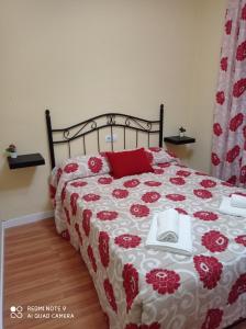 a bed with a red and white quilt with a phone on it at Casa Carrasco in Algar