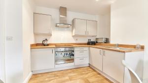 una cucina con armadi bianchi e lavandino di Roker boutique apartment a Sunderland