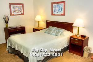 1 dormitorio con 1 cama grande, 2 mesitas de noche y 2 lámparas en Big Sky Motel, en Superior