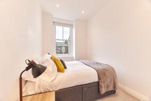 a white bedroom with a bed and a lamp at Barnes boutique apartment in Sunderland