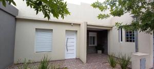 a white house with a door and a window at CASA VERDE 1 depto in Carhué