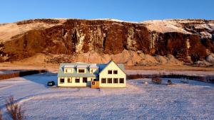 uma casa amarela em frente a uma montanha em Paradise Cave Hostel & Guesthouse em Hvolsvöllur