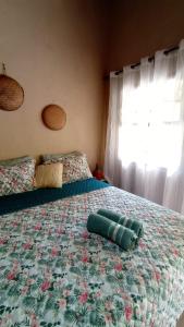 a bedroom with a bed with a floral bedspread and a window at Canto do Sabiá PETAR Hospedagem in Iporanga