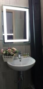 ein Waschbecken mit einem Spiegel und Blumen darauf in der Unterkunft ЖК Бестужевские сады 3 этаж in Kharkov