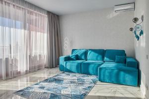 Sofá azul en la sala de estar con ventana en Familiya Apartments, en Hurzuf