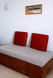 un letto con due cuscini rossi sopra di Isavella's Apartment a Skhoinoussa