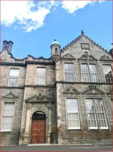 エディンバラにあるCentral Mezzanine Apartment in Historic Schoolの赤いドアと窓のある古いレンガ造りの建物