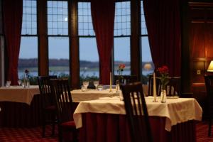 a dining room with tables and chairs and windows at Bunchrew House Hotel in Inverness