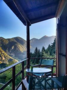 una mesa y sillas en un porche con vistas a las montañas en Dryades Guesthouse, en Ano Chora