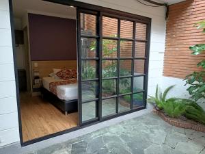 Habitación con cama y puerta de cristal grande. en Hotel Poma Rosa, en Medellín