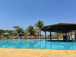 a large swimming pool with a pavilion and palm trees at Tijota Hotel Fazenda in Ipatinga