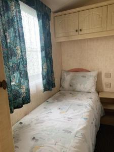 a small bedroom with a bed and a window at Lovely 4 berth static caravan, Marine Holiday Park, Rhyl, Wales in Rhyl