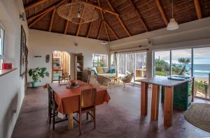 a living room with a table and chairs and the ocean at Pura Vida Tofo Beach Houses in Praia do Tofo
