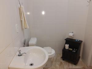 ein weißes Bad mit einem Waschbecken und einem WC in der Unterkunft Suítes Ninho da Águia Saquarema in Saquarema