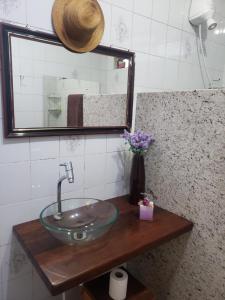 a bathroom with a sink and a vase of flowers at Suite com ar in Jaú