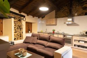 sala de estar con sofá marrón en la cocina en As Veneiras Casa Rural, en Neipín