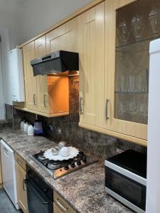 a kitchen with wooden cabinets and a stove top oven at Heart of George street / Oban / Argyll in Oban