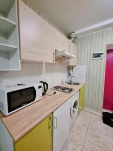 a small kitchen with a microwave and a sink at Сomfort24 Апартаменти на проспекті Гагаріна Мечнікова Apartment on Gagarina in Dnipro