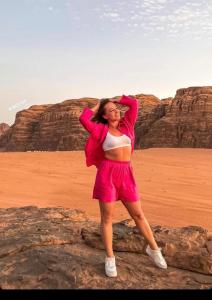 a woman standing on a rock in the desert at Mazayen Rum Camp in Wadi Rum