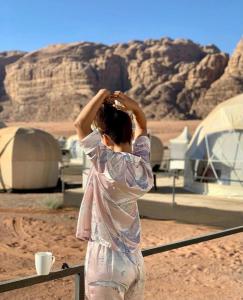 a woman standing in the desert adjusting her hair at Mazayen Rum Camp in Wadi Rum