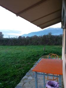 einem roten Tisch unter einer Veranda mit einem Feld in der Unterkunft Το μικρό σπίτι στο λιβαδι in Ioannina