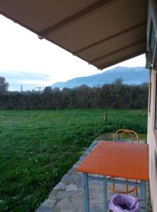 a red table sitting under a porch with a field at Το μικρό σπίτι στο λιβαδι in Ioannina