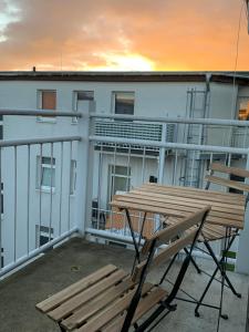 un banc et une table sur un balcon avec un coucher de soleil dans l'établissement Blue Chili 21 - Großzügige Altbauwohnung bis 7 Personen WLAN Balkon, à Magdebourg