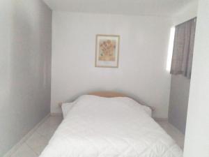 Un dormitorio con una cama blanca con una foto en la pared en Le Trèfle d'Or en Gérardmer