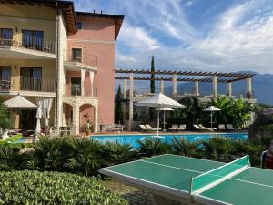a pool with a tennis court in front of a building at Residenza Le Due Torri in Riva del Garda