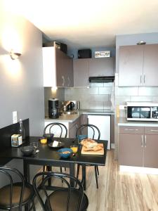 a kitchen with a black table and chairs and a kitchen with a counter at Appartement 4 personnes au pied des pistes in La Pierre Saint Martin