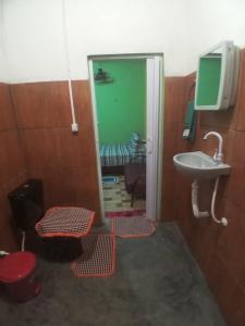 uma casa de banho com um lavatório e uma porta com tapetes vermelhos em Casa Gael (Gisele & Lucimar) em Atins
