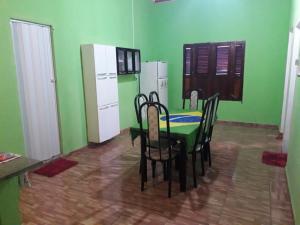 eine grüne Küche mit einem Tisch, Stühlen und einem Kühlschrank in der Unterkunft Casa Gael (Gisele & Lucimar) in Atins