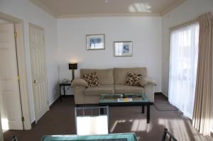 ein Wohnzimmer mit einem Sofa und einem Tisch in der Unterkunft Tuscany Villas Whakatane in Whakatane
