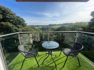 three chairs and a table on a balcony with a view at Woodroyd apartments in Luddenden Foot